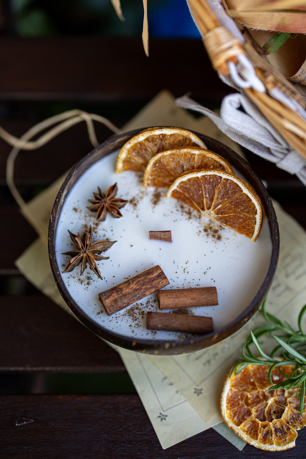 Scented candle bowl with white wax, orange slices, cinnamon sticks, star anise on table