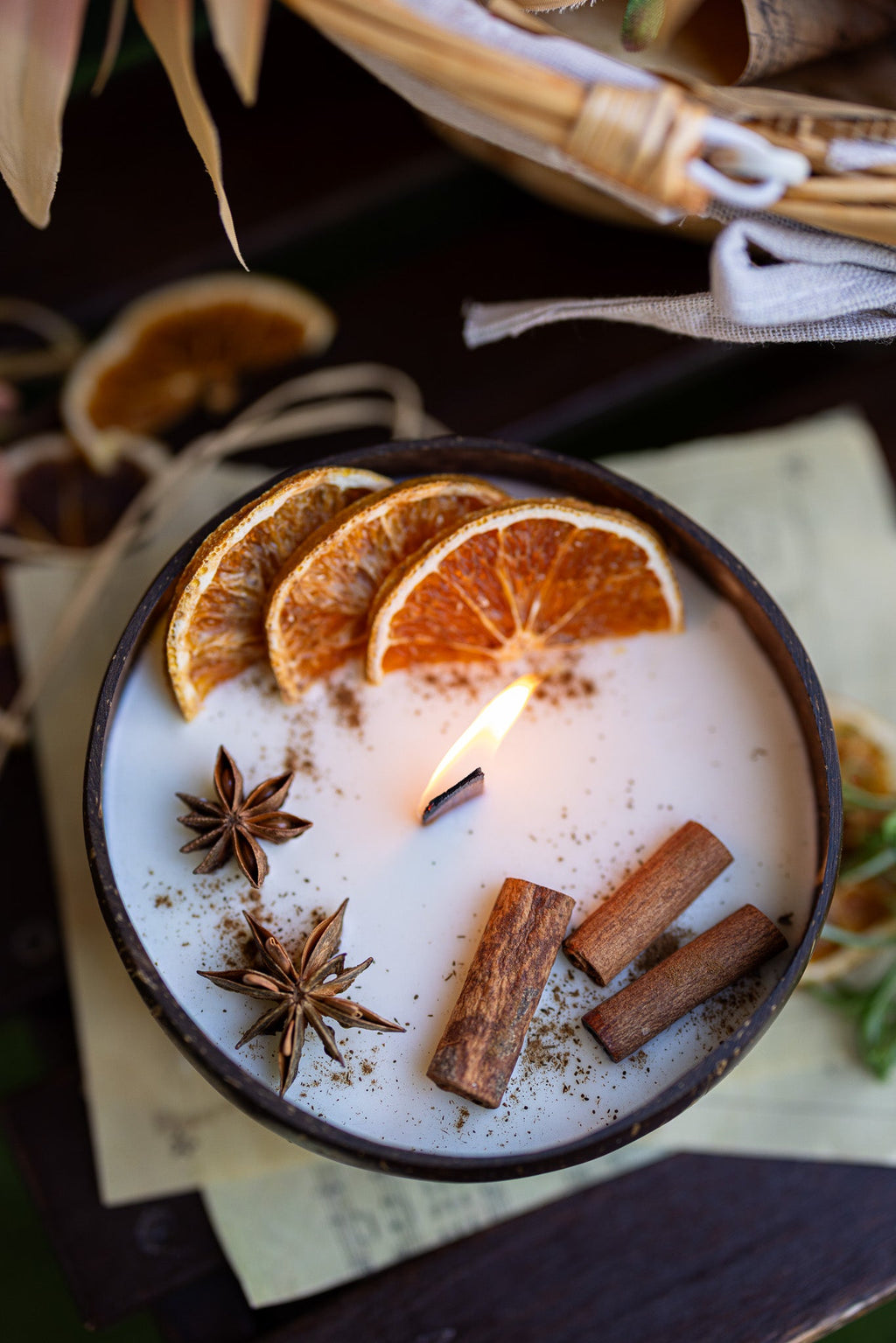 Coconut scented candle with orange slices, cinnamon sticks, and star anise in round bowl