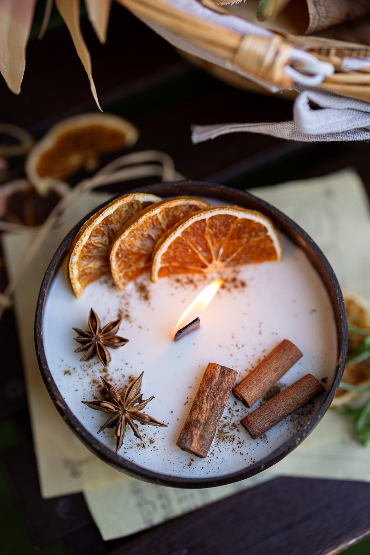 Coconut scented candle with orange slices, cinnamon sticks, and star anise in round bowl