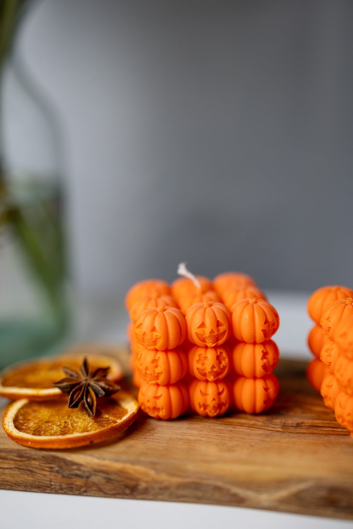 Orange pumpkin face bubble soy candle on wooden board with star anise and citrus slice