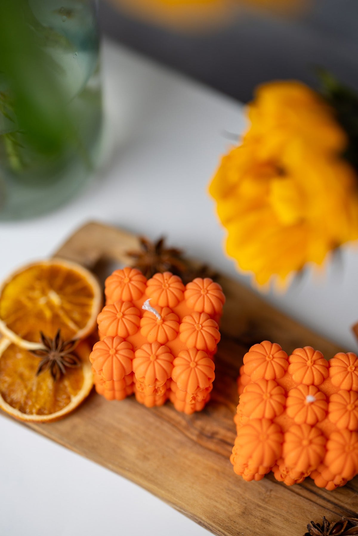 Orange pumpkin face bubble soy candles with star anise and orange slices on wooden tray