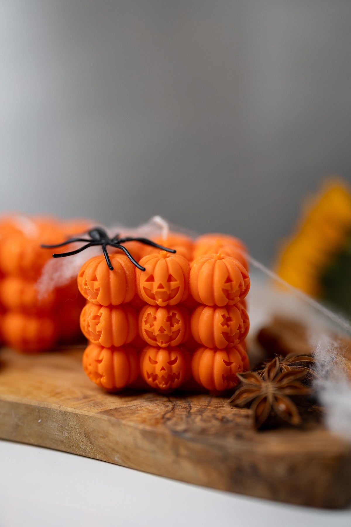 Orange pumpkin face bubble soy candle with small carved stem detail on wooden board