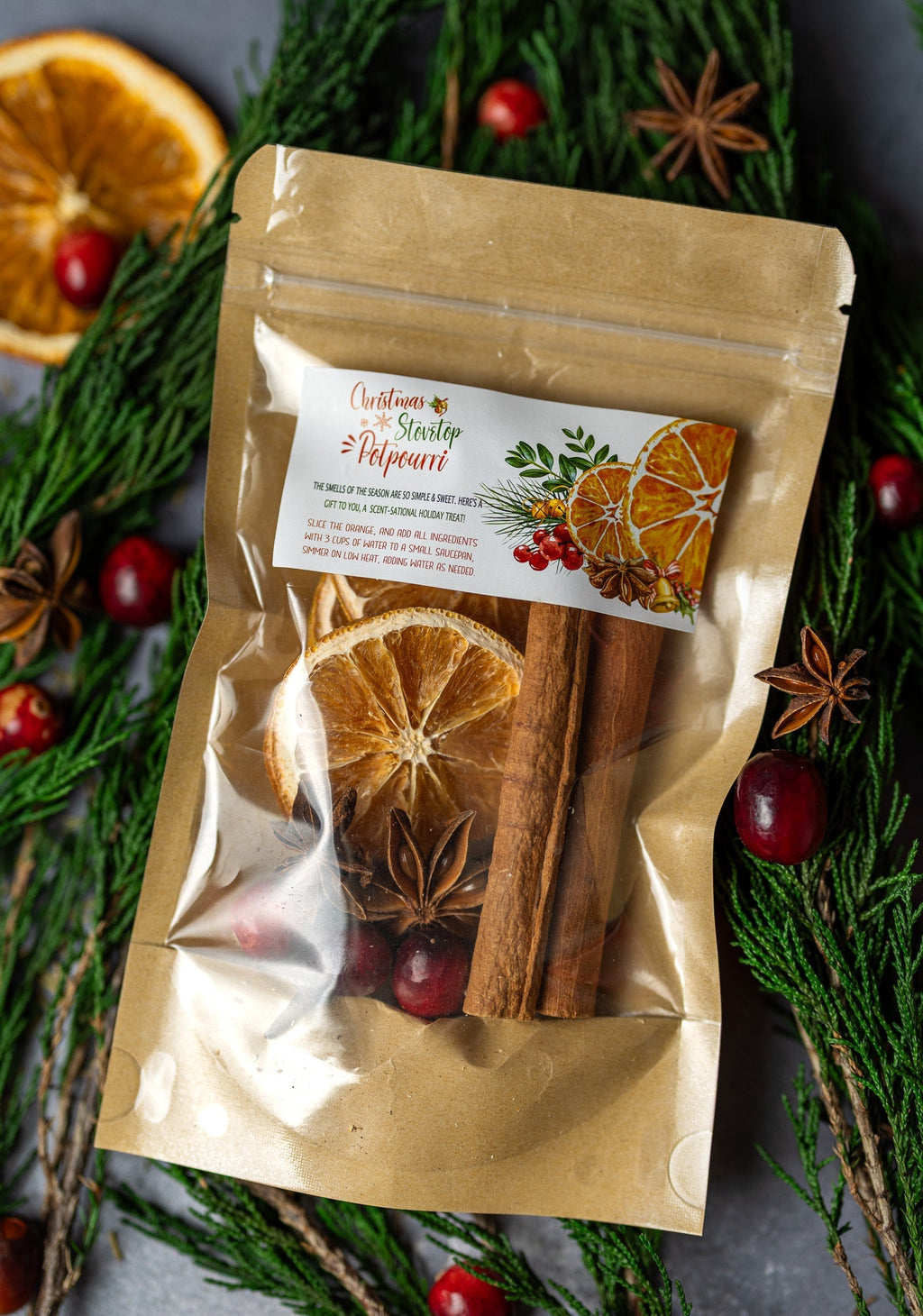 Stovetop potpourri pouch on pine branches with orange slices and cinnamon sticks