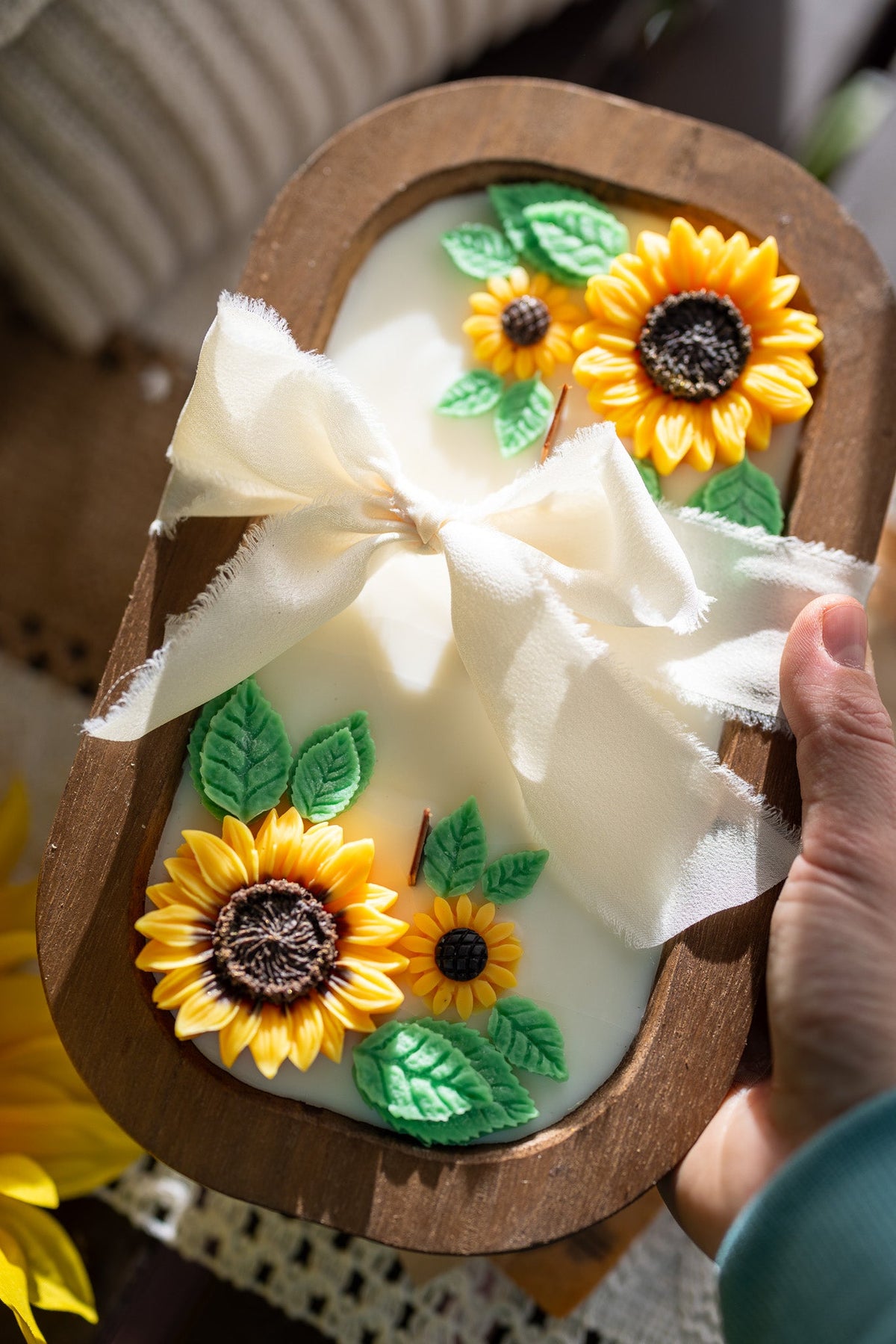 Wooden sunflower soy wax candle with yellow flowers, green leaves, and white ribbon bow in oval holder