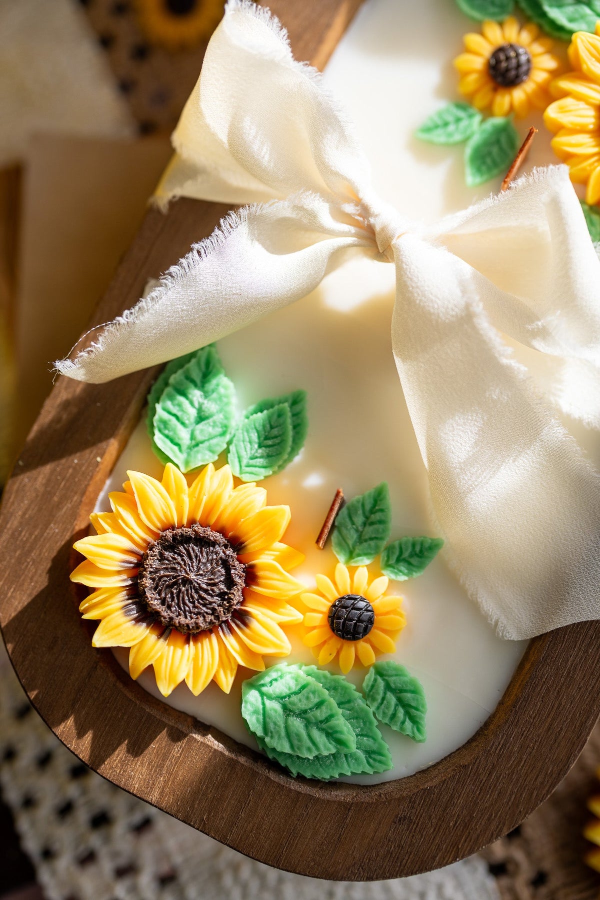 Wooden oval sunflower soy wax candle with yellow blooms, green leaves, and large white ribbon bow