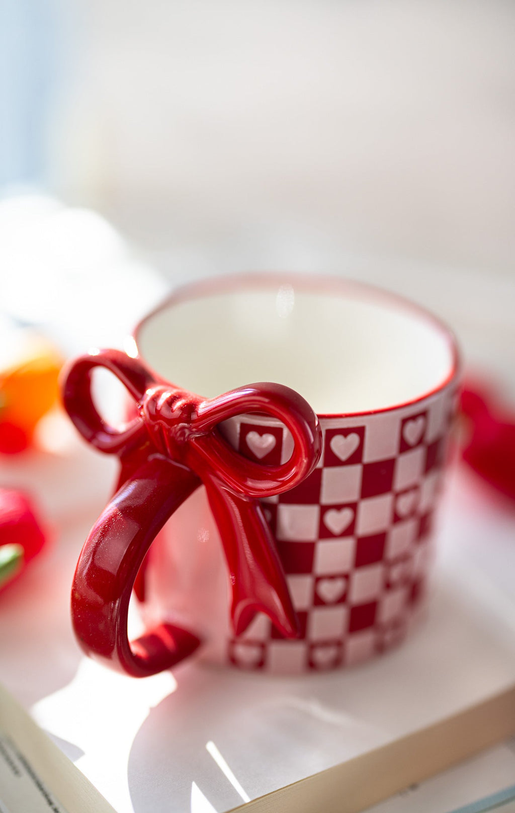 Ceramic mug in red and white with checkerboard hearts and heart-shaped bow decoration
