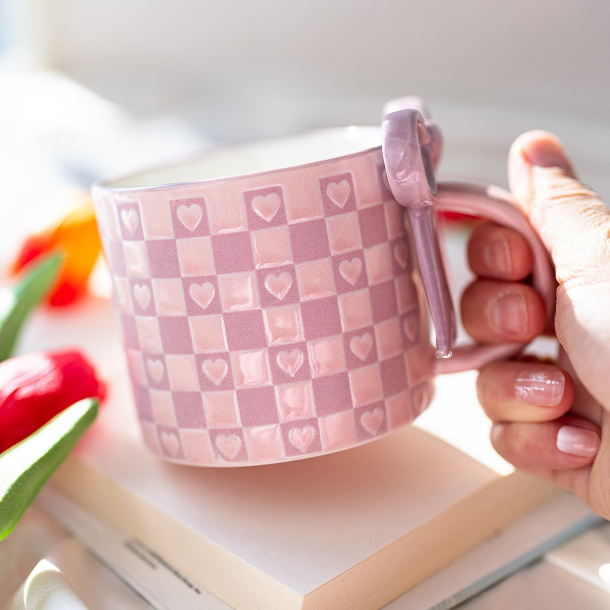Ceramic mug in pale pink with checkered heart pattern and bowknot handle decoration