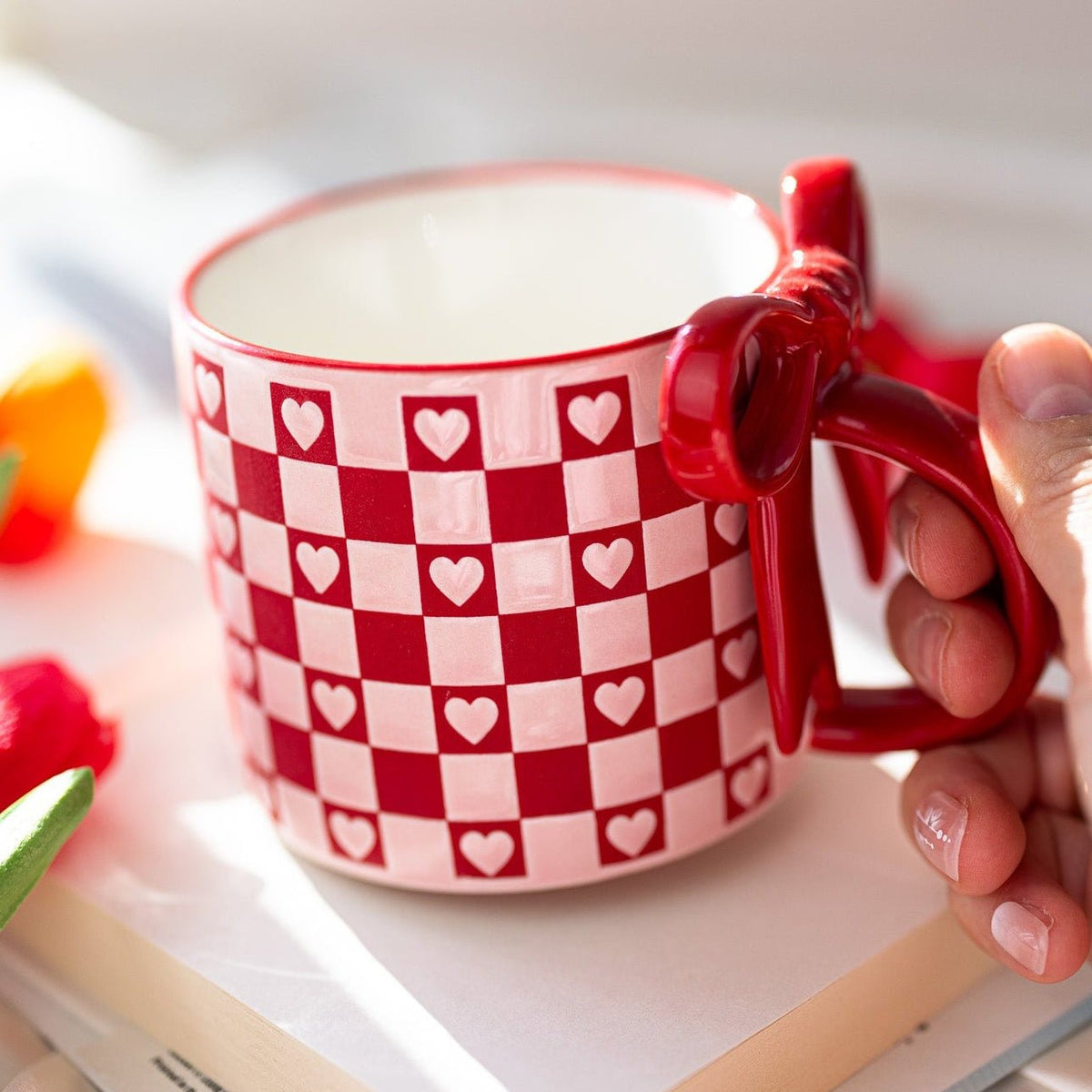 Ceramic mug in red and white with checkerboard hearts and bowknot-style handle