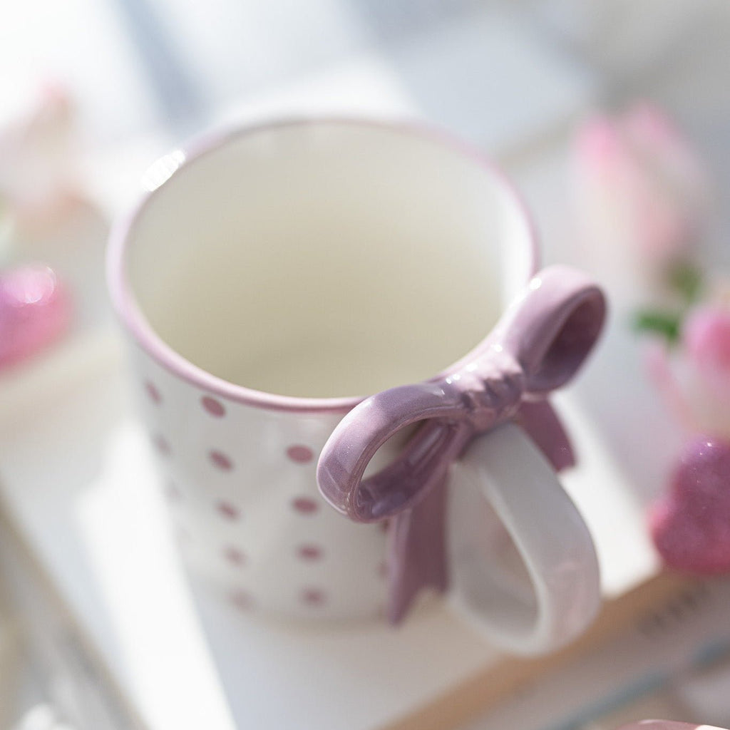 White ceramic mug with pink polka dots and pink ribbon bowknot handle