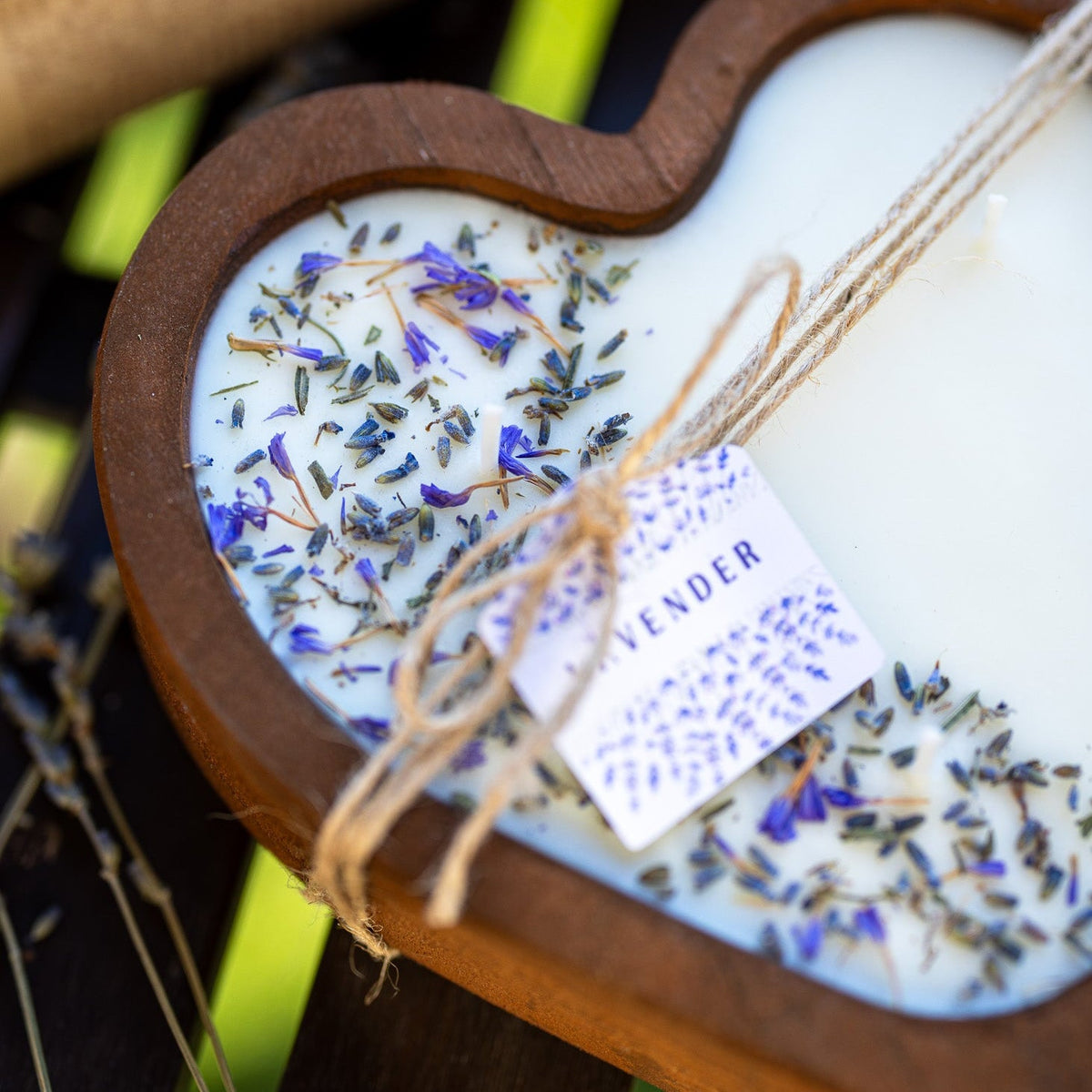 Close-up heart-shaped wooden candle bowl with white wax, lavender sprigs, and wick bundle.