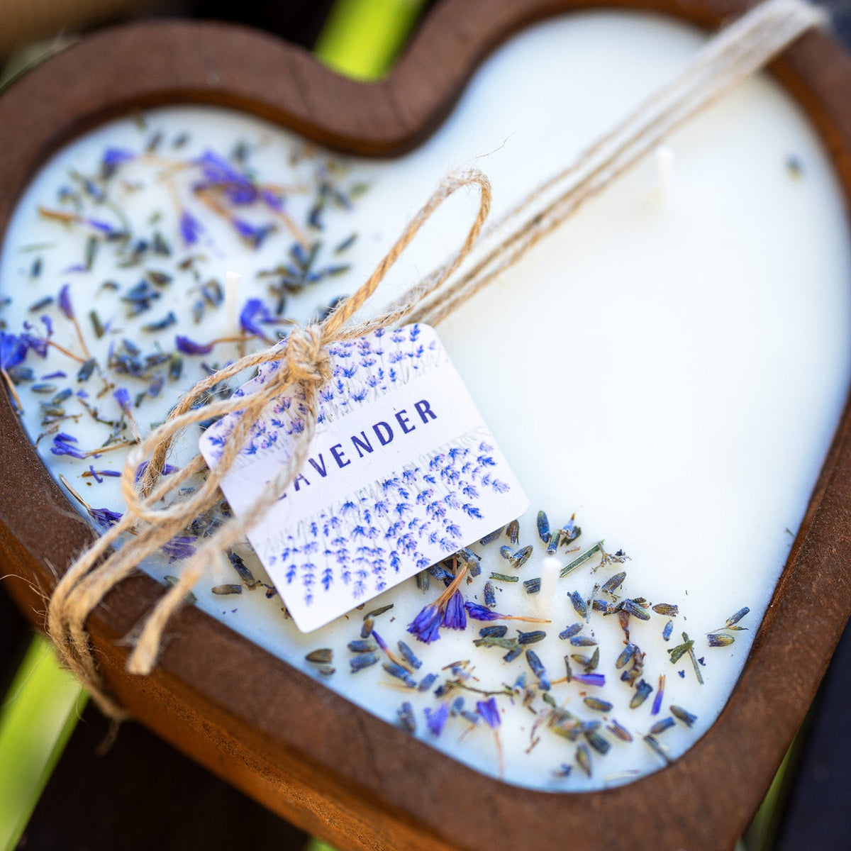 Heart-shaped wooden candle bowl with white wax, lavender flowers, and twine-tied wick.