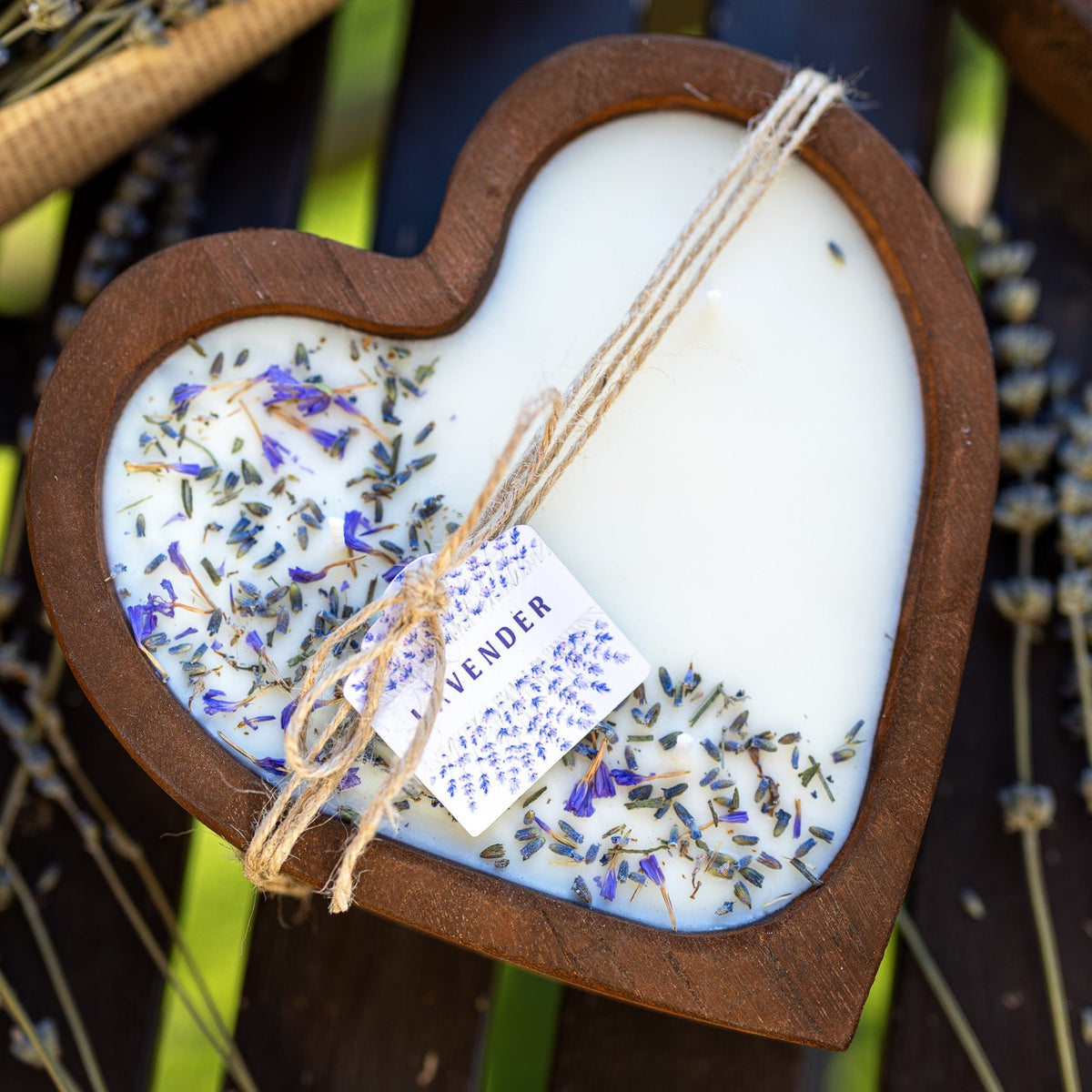 Heart-shaped wooden bowl candle with white wax, lavender sprinkles, and twine wick in center.
