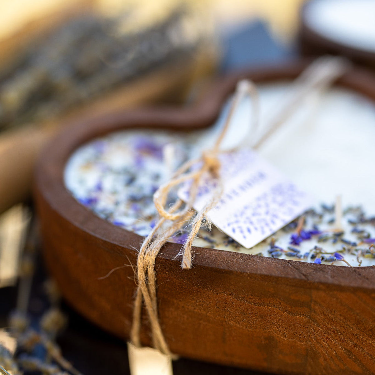 Heart-shaped wooden candle bowl with white wax, lavender bits, and bundled wick detail.