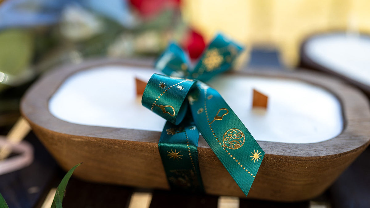 Wood dough bowl candle top view with white wax and teal ribbon bow on brown wooden bowl