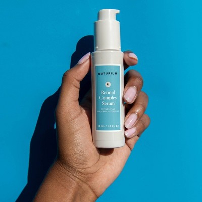 Naturium retinol complex serum bottle held in hand, pump top visible