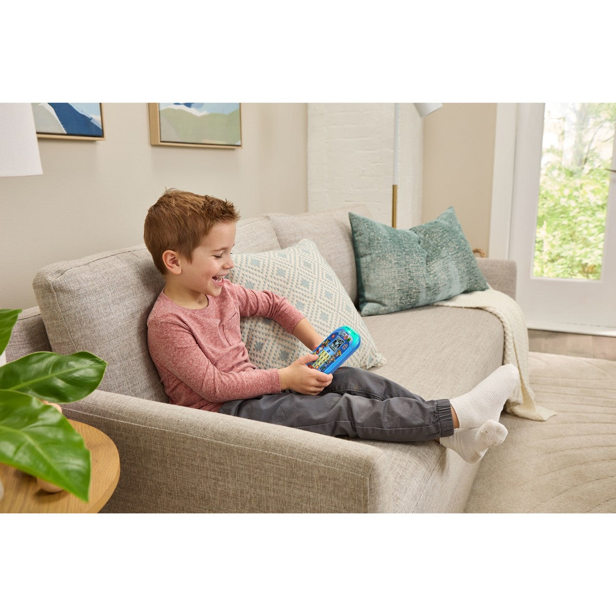 Child holding a blue learning phone toy with paw buttons and number keypad
