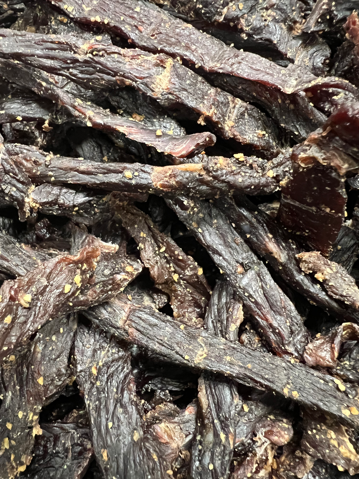 Garlic beef jerky strips, glossy dark dried meat pieces