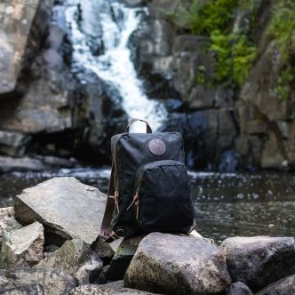 Olive green backpack with round logo patch and front zipper pocket