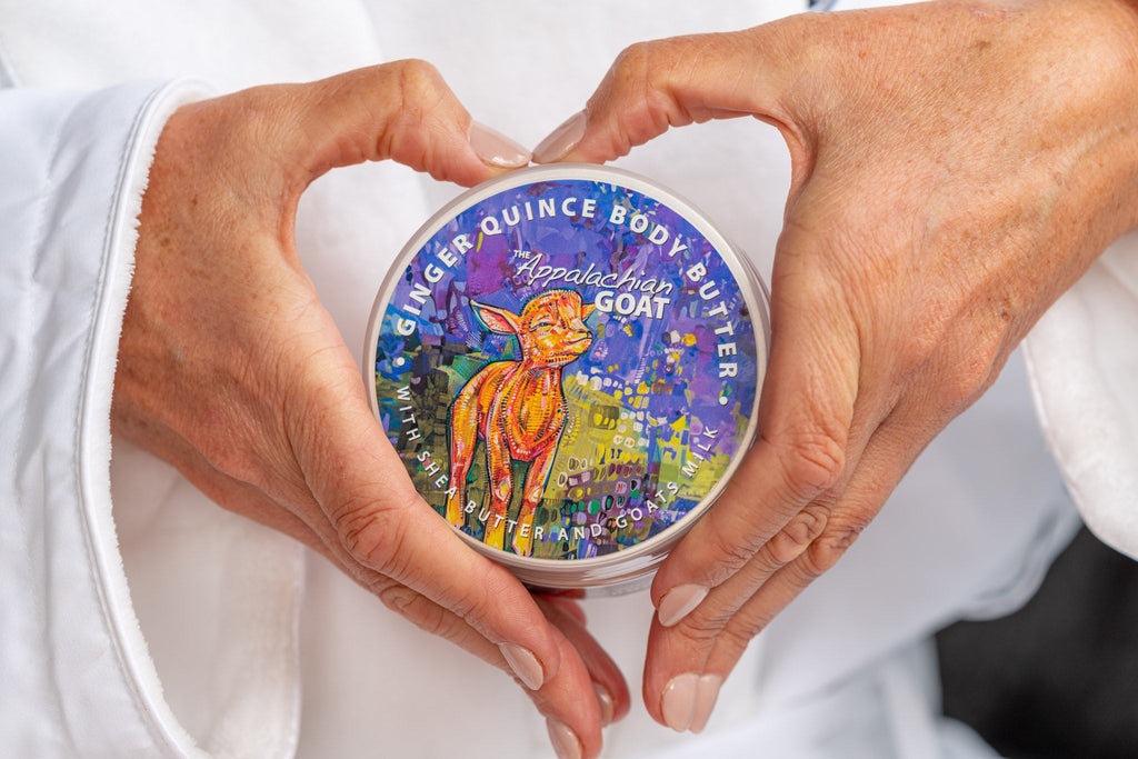Goat milk body butter jar held between hands, round blue printed lid