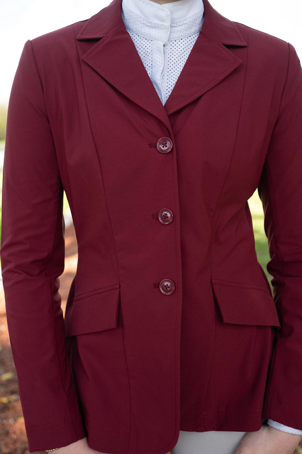 Burgundy show coat close-up with three-button front and flap pockets