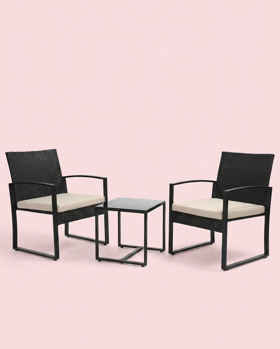 Studio view of 3-piece patio set: two dark woven chairs with cream cushions and square table