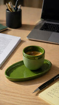 Green ceramic espresso cup resting on a matching green saucer.