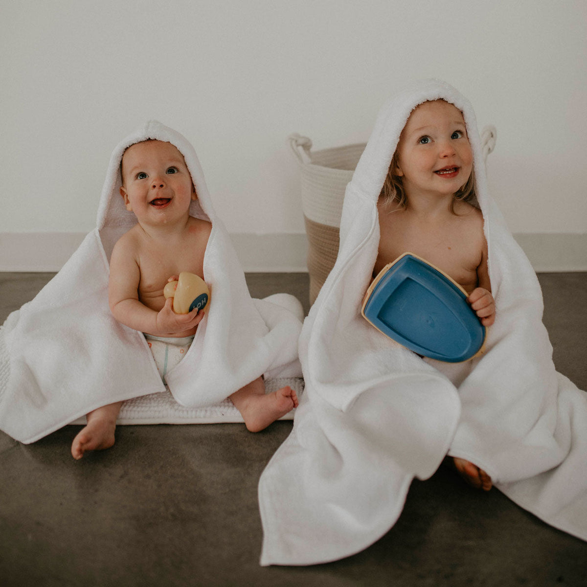 White hooded bath towel draped around a baby with open hood
