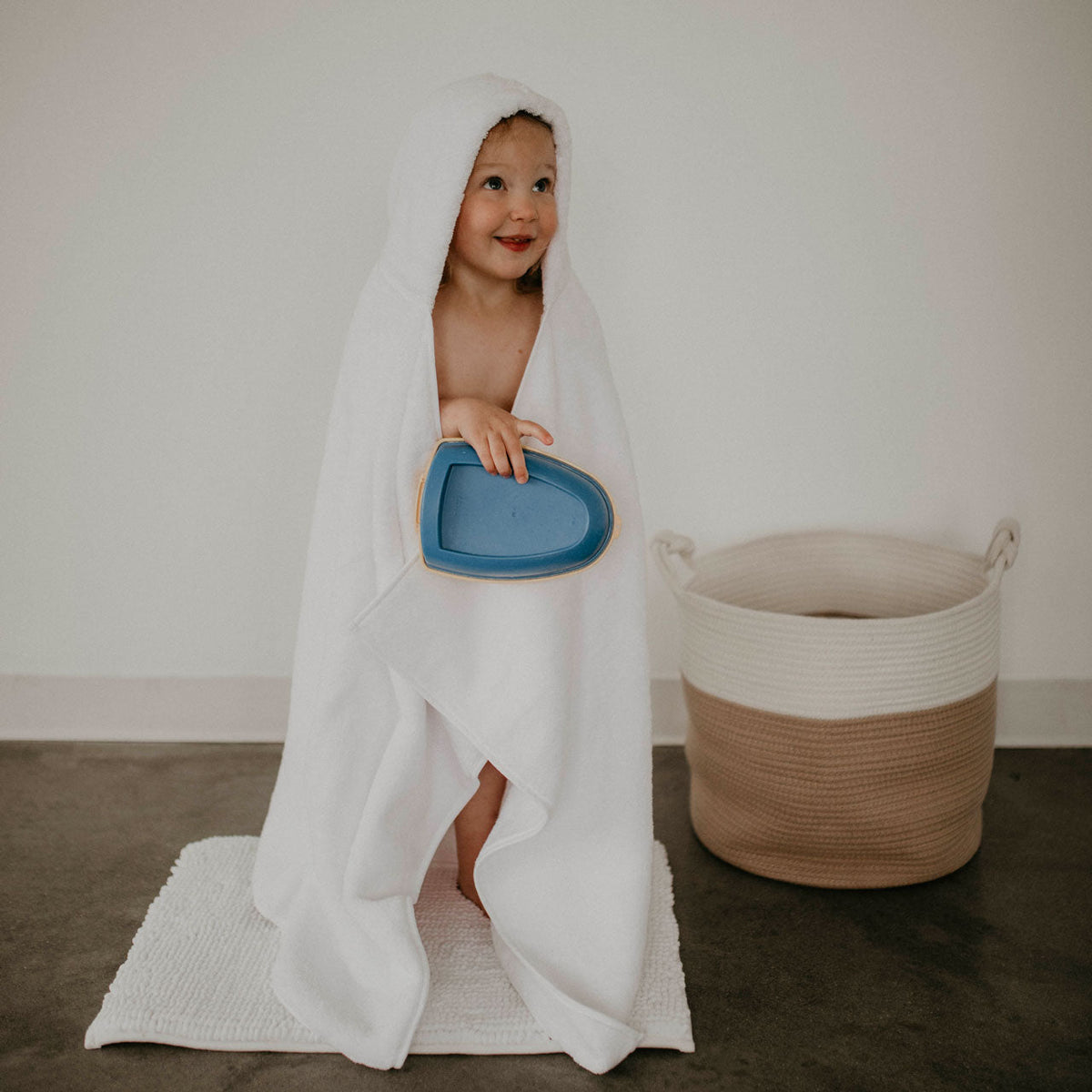 White hooded bath towel with baby standing in robe wrap with hood up