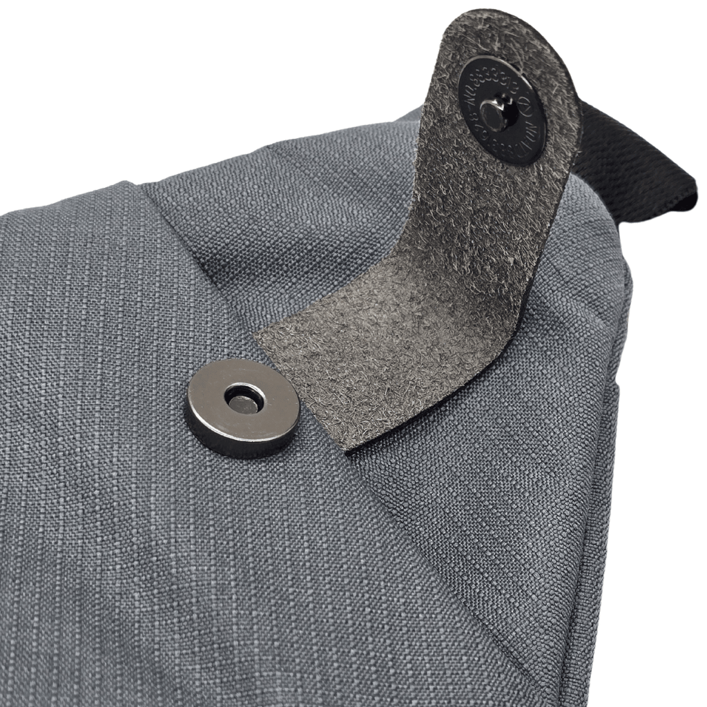 Close-up of gray bag strap connector with round metal snap button