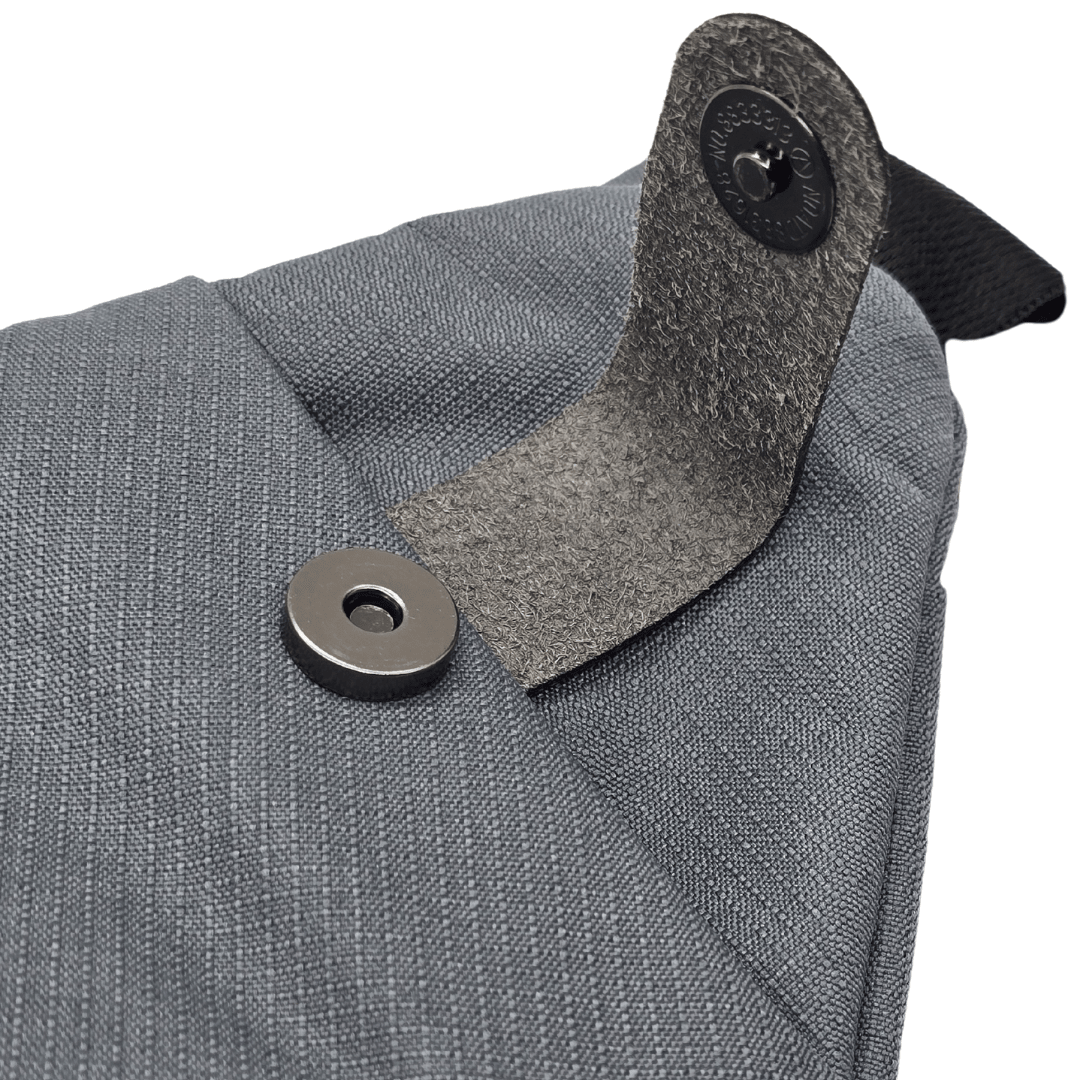 Close-up of gray bag strap connector with round metal snap button