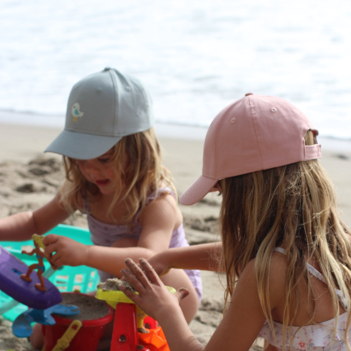 Pastel pink baseball cap with strawberry embroidery on front, worn by a child