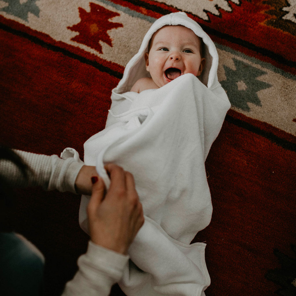 White hooded bath towel with baby in hooded robe, arms tucked inside