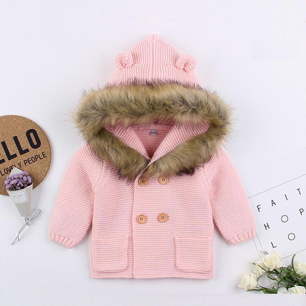 Light pink knit hooded baby jacket with faux fur trim and button front