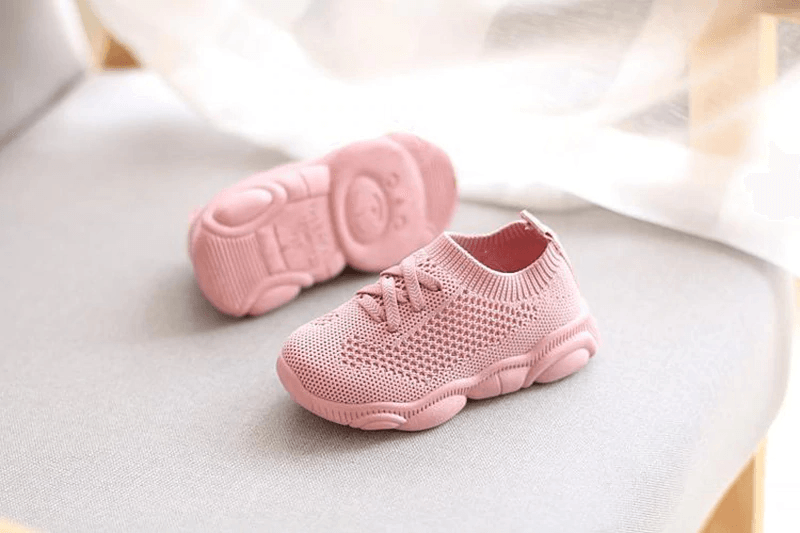 Pink knit baby sneakers with matching pink outsole and lace-up front