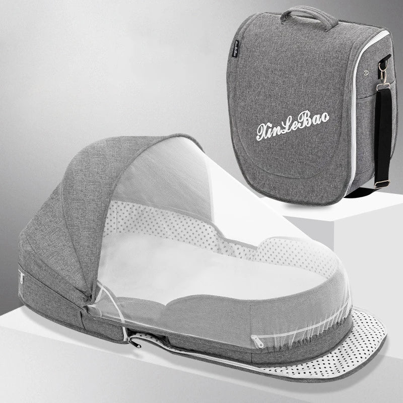 Grey folding baby bassinet with canopy, mosquito net, and portable carry bag