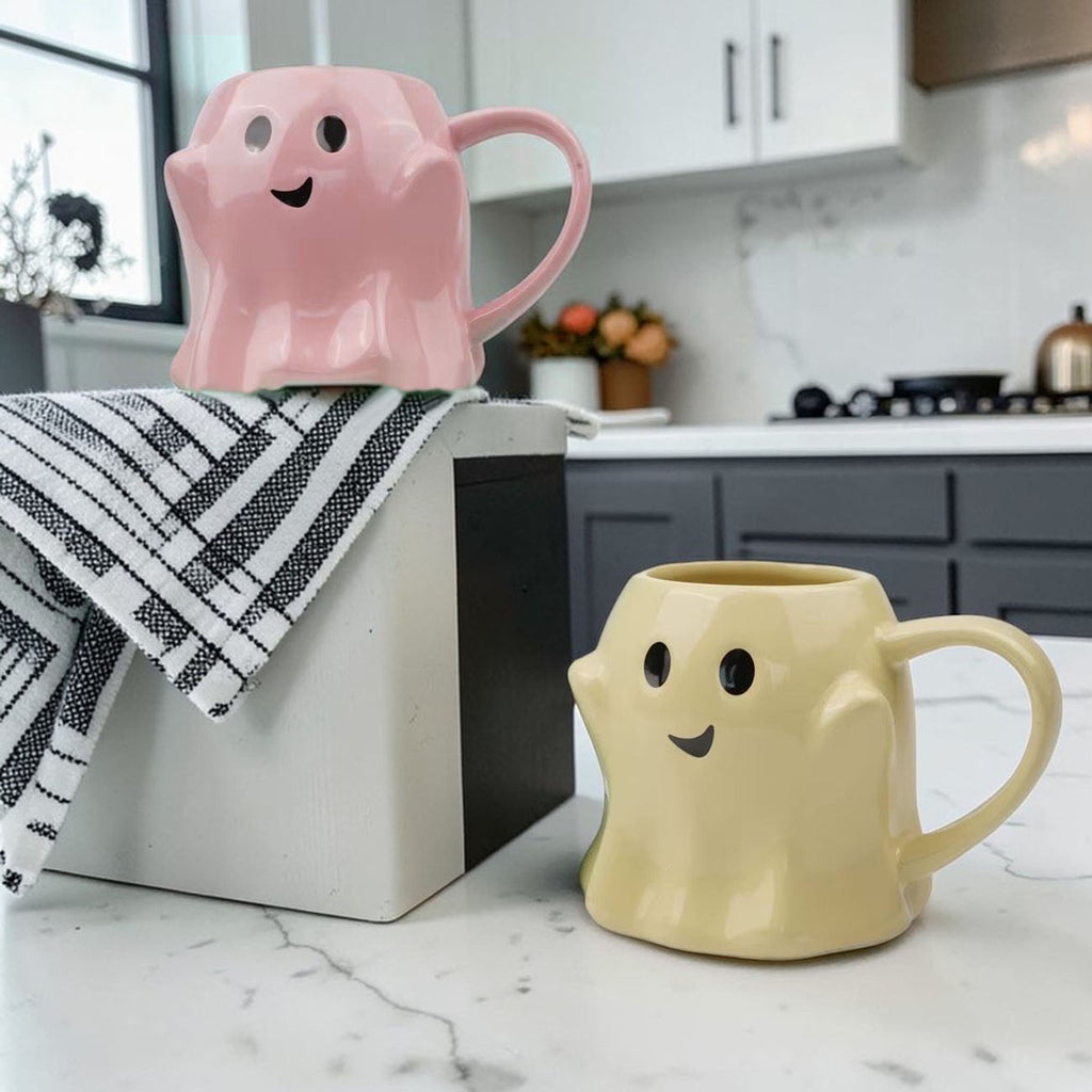 Pink ghost-shaped ceramic mug with smile face, rounded handle and open top