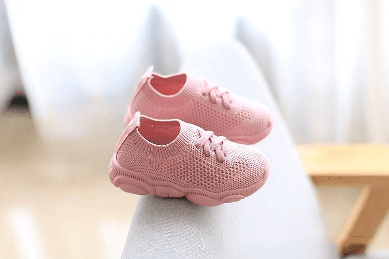 Pink knit baby sneakers with lace-up closure and thick cushioned soles