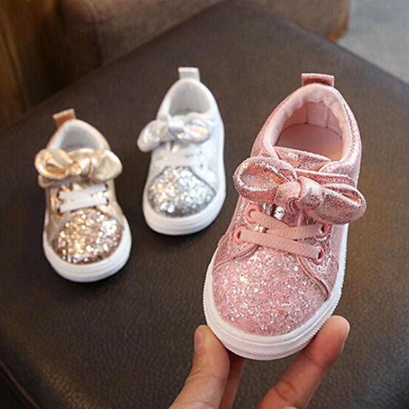Girls pink glitter lace-up sneakers with bow detail and white rubber sole.