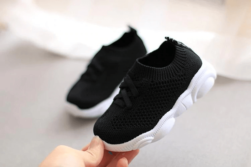 Black knit baby sneakers with lace-up front and white cushioned soles
