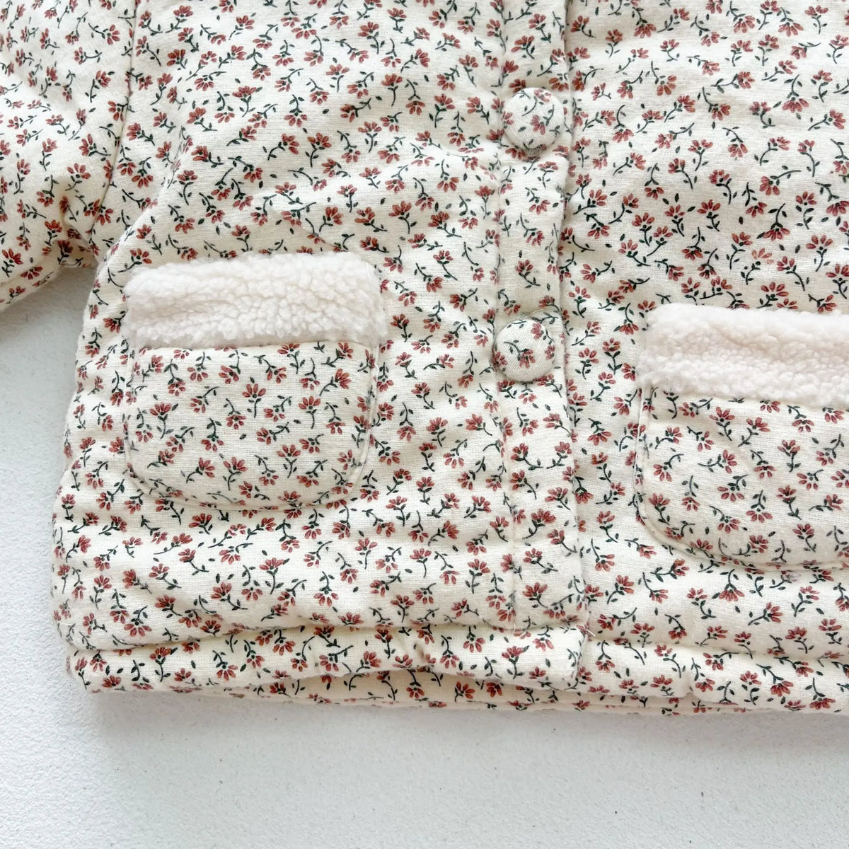 Thick floral quilted baby jacket with cream sherpa trims and front pocket openings
