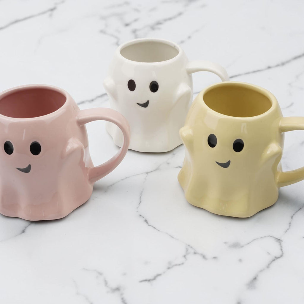 Set of three ghost-shaped ceramic mugs in pink, white, and yellow with handles