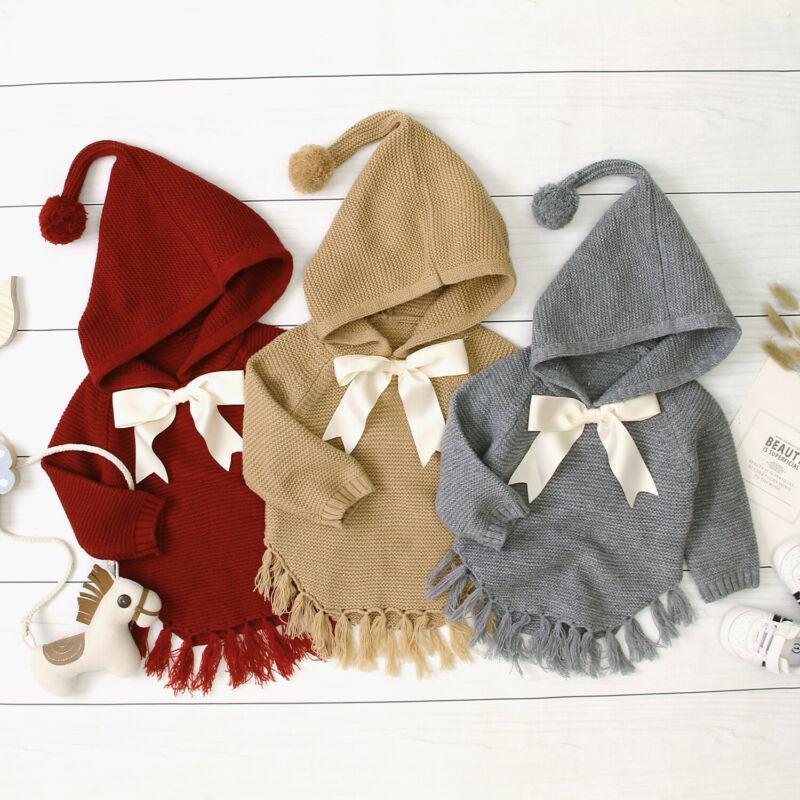 Three knitted hooded toddler pullovers with white bows and tassel-trim hems in red, khaki, gray