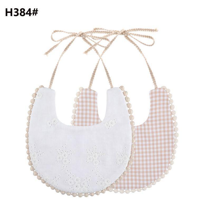 Infant double-sided bib with tassel ties, white eyelet front and peach check reverse