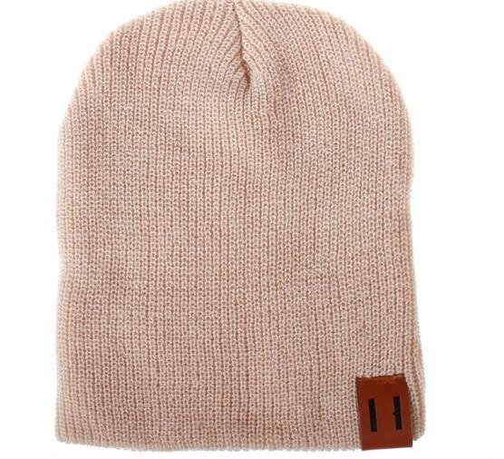 Beige knit beanie hat with foldover cuff and brown logo patch