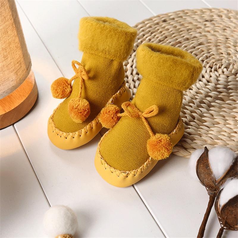 Newborn baby shoes in mustard yellow fabric with bow and pom pom trim