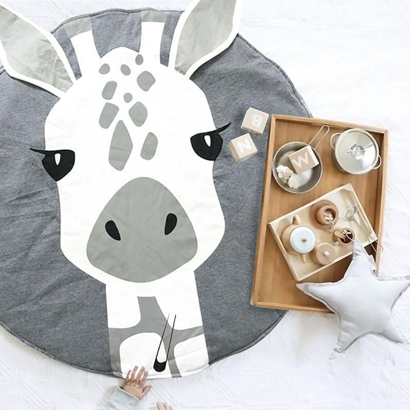 Round baby animal play mat with cow face print and play items on top.