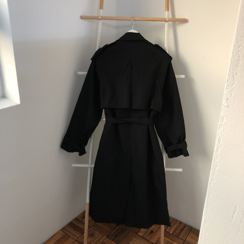 Black long overcoat on hanger, back view with belt and yoke seam
