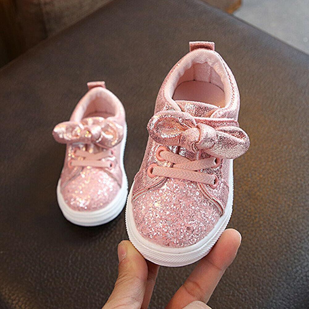 Girls pink glitter lace-up sneakers with bow detail, white rubber sole.