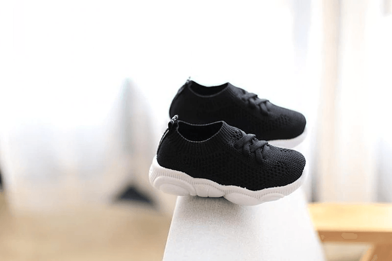 Black knit baby sneakers with lace-up closure and thick white cushioned soles