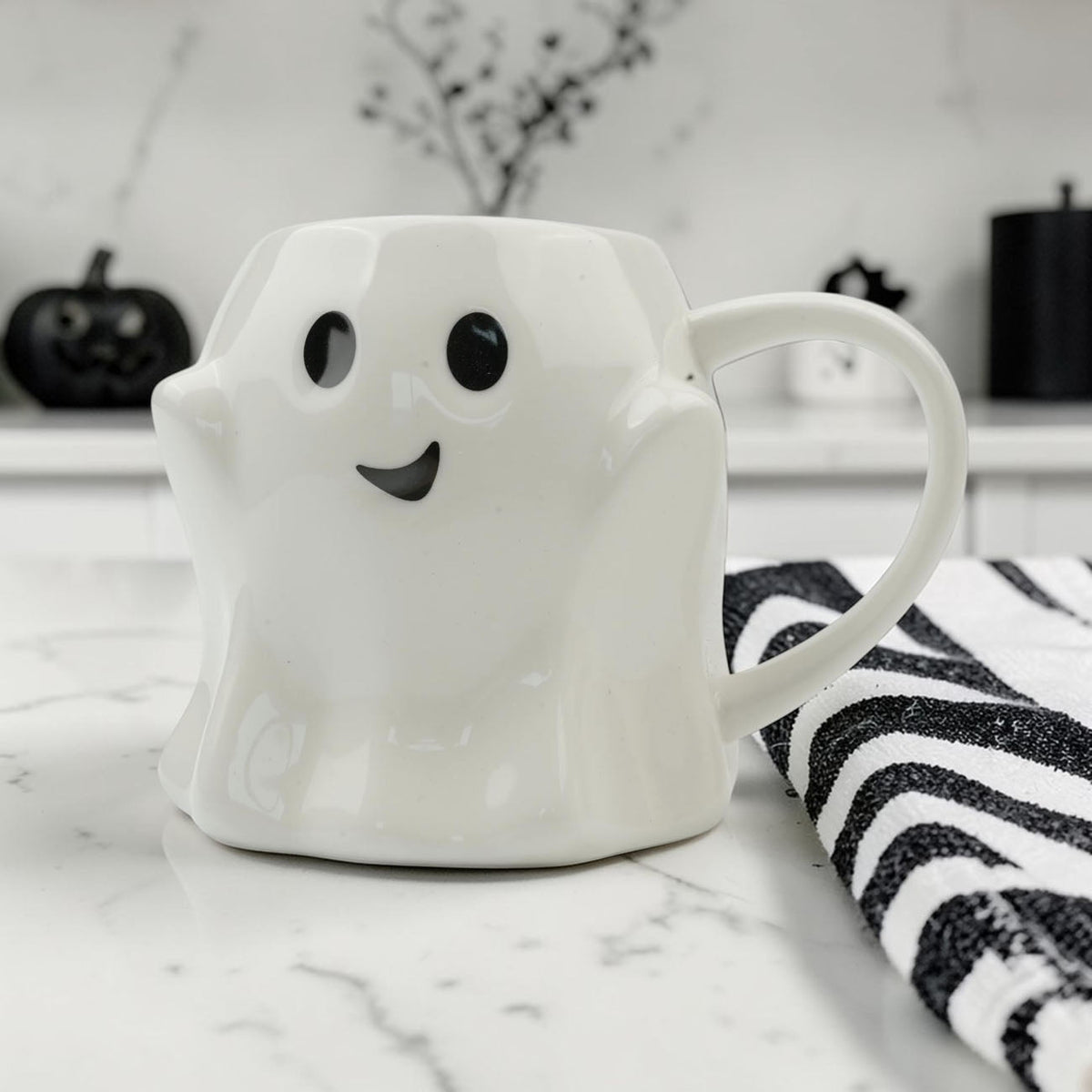 White ghost-shaped mug with black eyes and a curved smile